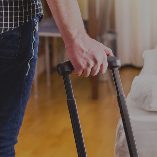 Person pulling suitcase into hotel room
